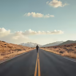 person riding on the back of a motorcycle down a long stretch of road