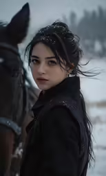 woman standing in front of her horse during a snow storm