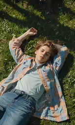 a young man laying in the grass on top of a blanket