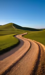 a dirt road going around two bend on one side of the hill
