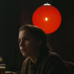 a woman looking down at a glass of liquid