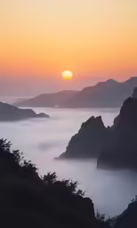 a view of mountains with the sun rising in the distance