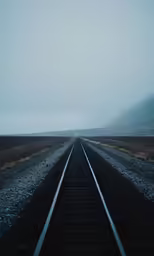 long train tracks lead into the distance along an empty track
