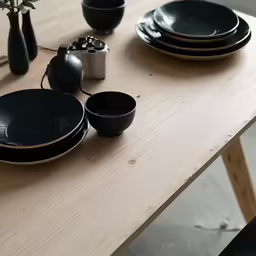 a table that has been set with many different black dishes