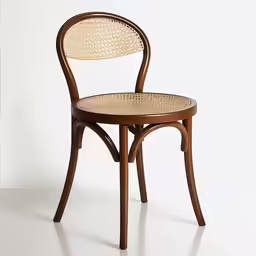 an empty wooden chair with cane seat on white surface