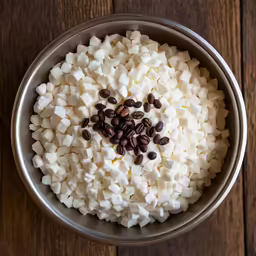 a pan filled with chocolate beans, chopped white sugar and uncooked marshmallows