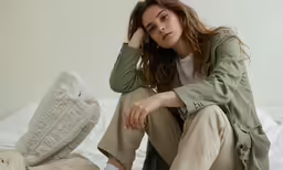 woman in light clothing sitting on bed with a pillow