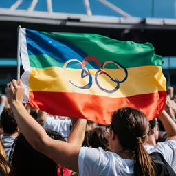 a woman holds up the flag for the olympics
