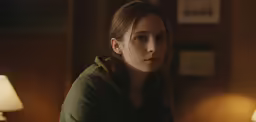a woman looking pensive at the camera in a darkened room