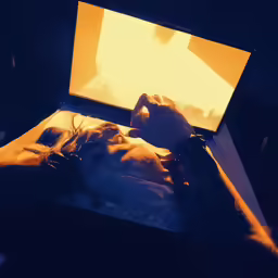 person laying on their back and looking at a computer screen