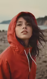 a young woman in a red jacket on the beach