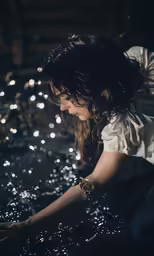 a woman crouching over some water in the dark