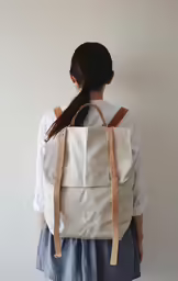a woman with white backpack and a brown bag