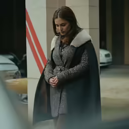 a woman standing next to a tall pillar in a city