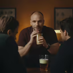 two men sitting at a table with drinks