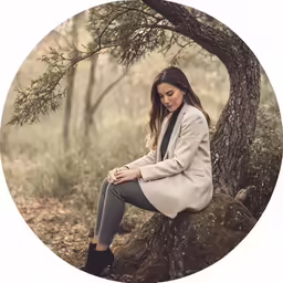 a woman in a coat and boots sitting on the ground