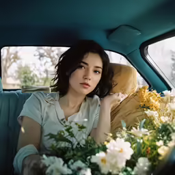 a woman sitting in the back of a car next to flowers