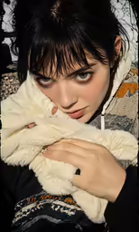 a woman looking at the camera and holding her coat over her shoulders