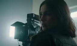 the woman in the black jacket is behind a video camera