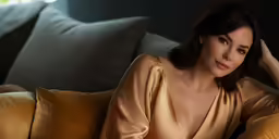 a sexy woman with brown hair laying on a couch
