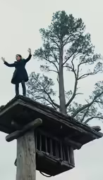 a woman standing on the edge of a building with her arms spread wide