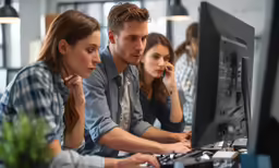 three young professionals working at computers in a bright office