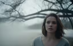 a woman standing by a tree and foggy park