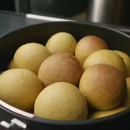 several yellow lemons inside a silver metal pan