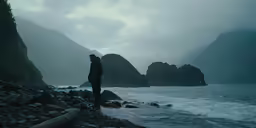 a man is standing on rocks looking at the water