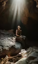 a woman sitting in a cave looking off into the distance
