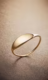 a yellow gold ring on top of a brown table