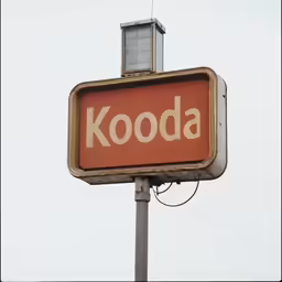 a kodak sign hanging from the side of a metal pole