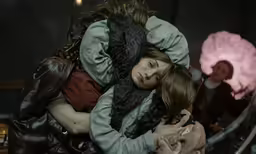 a woman hugging a woman sitting on top of a chair