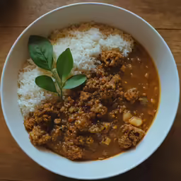 a bowl filled with meat, rice and green leaf