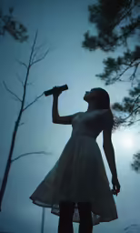 woman dressed in short dress drinking water with dark sky behind her