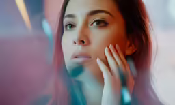 a beautiful woman looks through the glass while holding her hand to her face