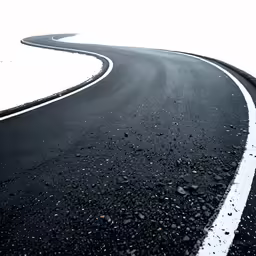 a winding road lined by snow and black rocks