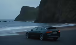 a gray car parked on the side of the road near an ocean
