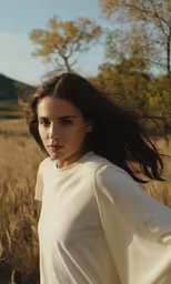the young woman poses for a photograph in the middle of an open field
