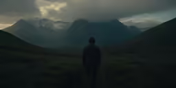 a man standing alone and looking towards the mountains