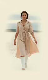 a woman walking down a beach carrying a brown bag