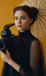 a woman posing with an umbrella holding a camera