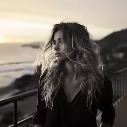 woman with long hair walking down sidewalk near ocean,a woman with long hair standing by the beach