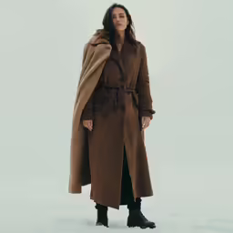 a woman standing in snow wearing an overcoat