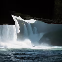 a person is in the water near a waterfall