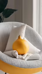 a pomegranate is sitting on a chair near pillows and pillows