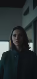 a woman with shoulder length black clothing standing next to a window