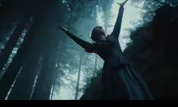 a woman in a dark dress reaching up to the air