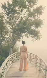 a woman standing on top of a wooden bridge