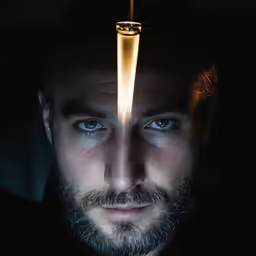 a man with blue eyes and a cigarette burning from a lighter